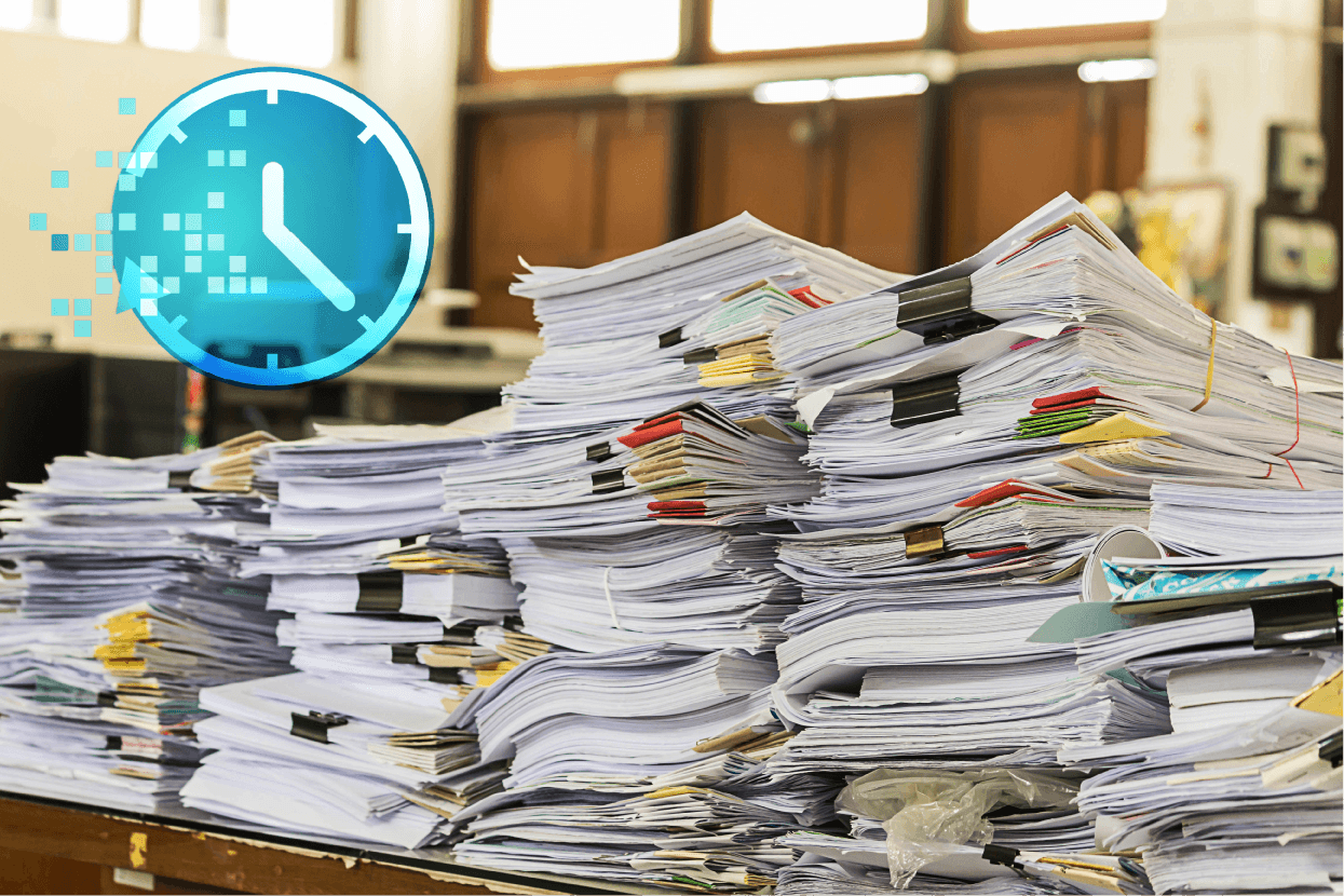 Large stacks of paper documents and files piled on office desk, illustrating records management challenges and the need for secure document storage and digitization.